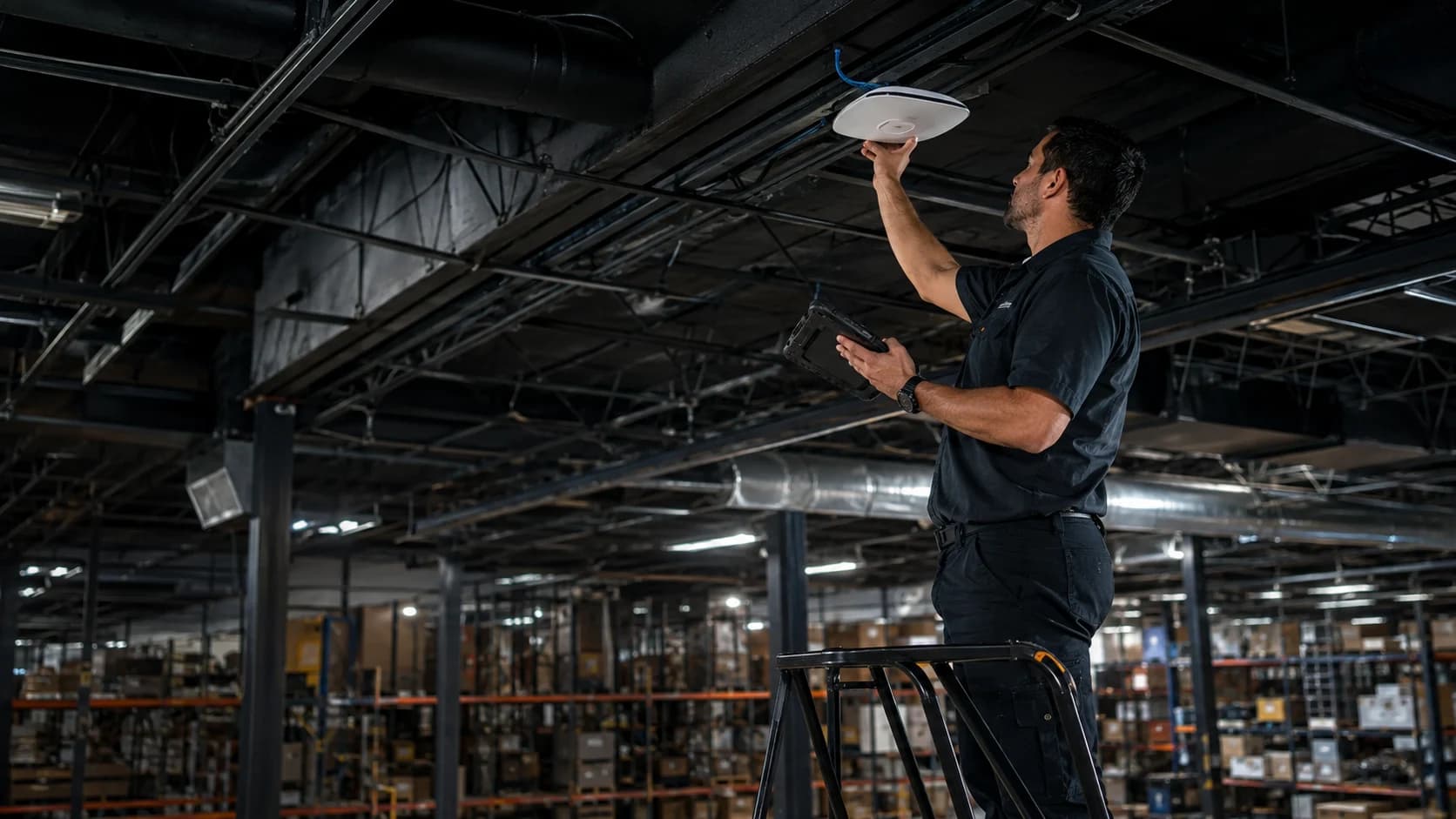Professional installer mounting and validating a commercial wireless access point in a warehouse